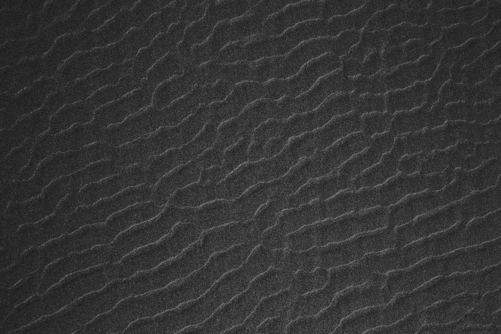 黑色材料简洁海滩上波浪纹的黑色沙石全景照背景图片