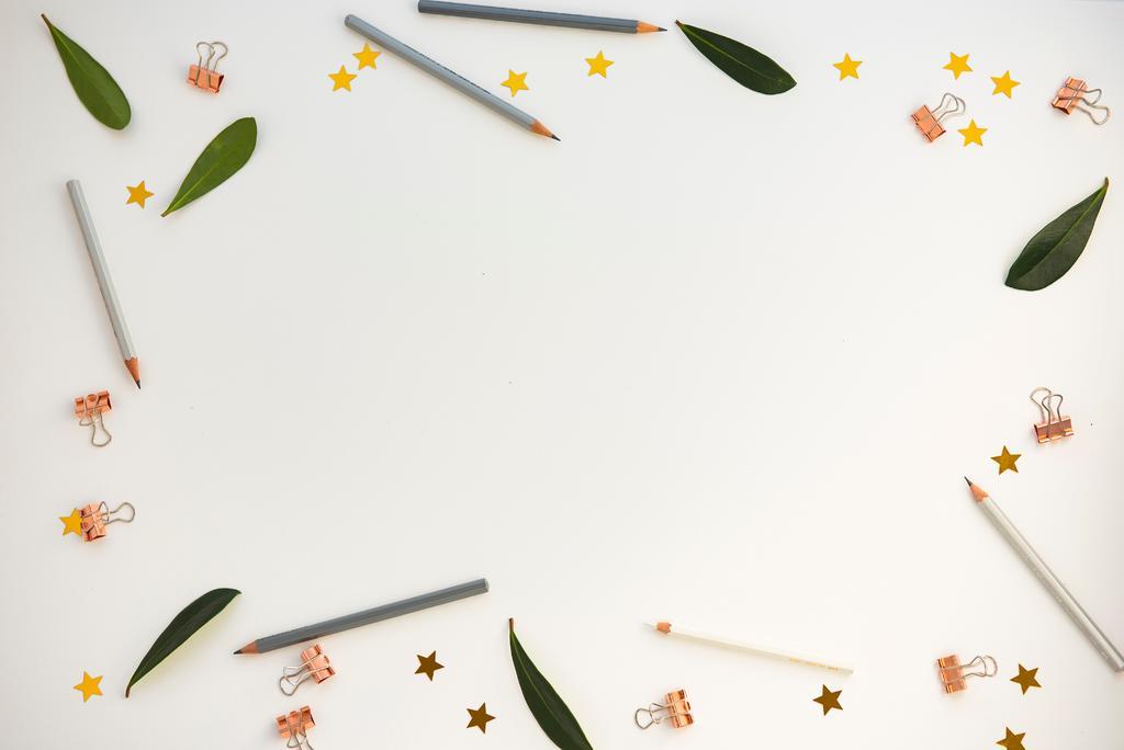 白色的桌子上的绿叶和夹子和笔背景图片