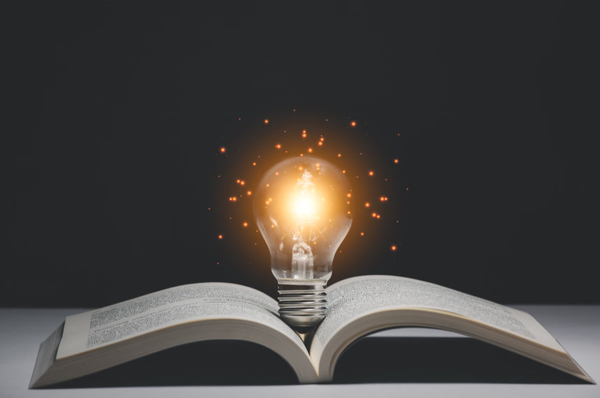 黑色背景摊开的书籍和发光灯泡素材