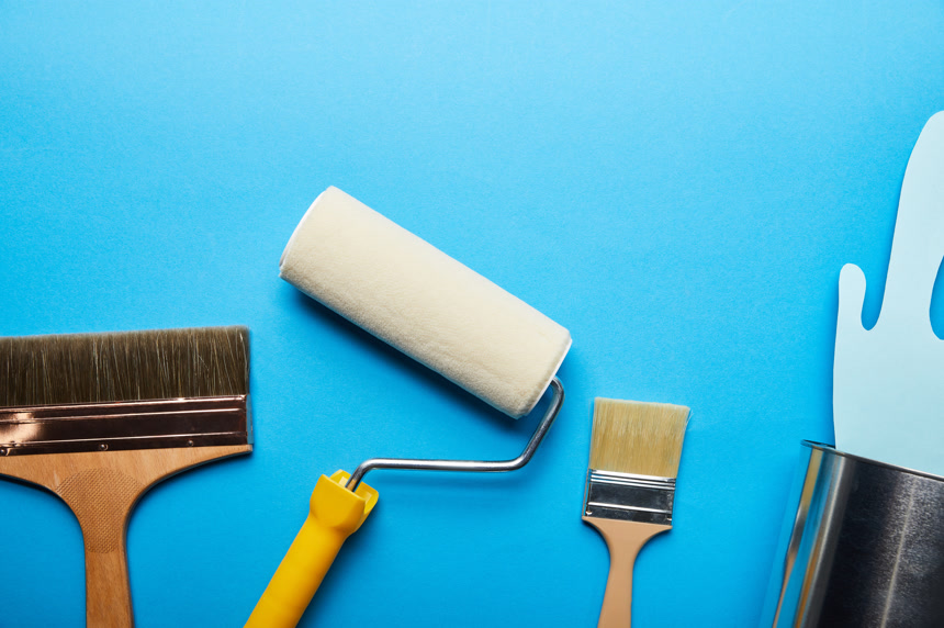 从金属罐附近的刷子和滚筒附近溢出的剪纸蓝色油漆粉刷工具