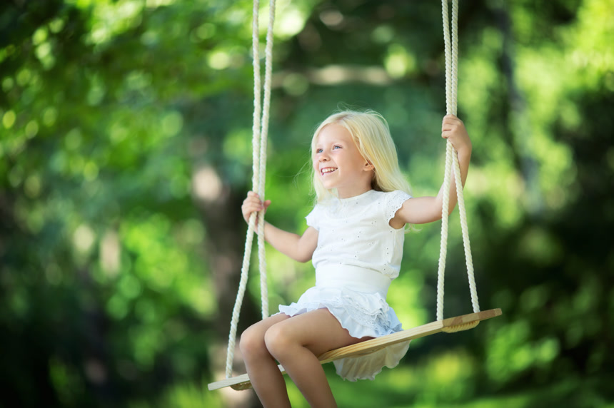 小女孩坐在秋千上快乐自由的玩耍在公园里 