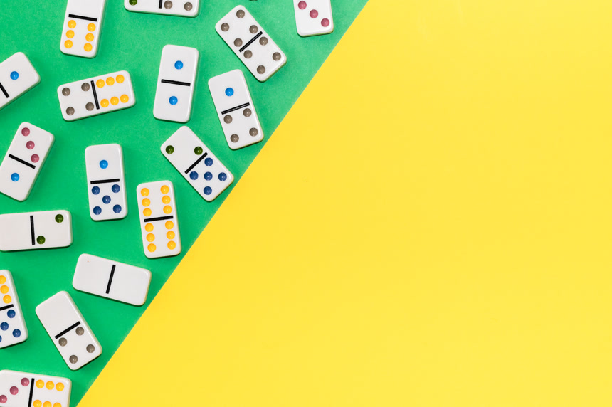 带有彩色圆点的白色多米诺骨牌杂乱地躺黄绿色背景桌游