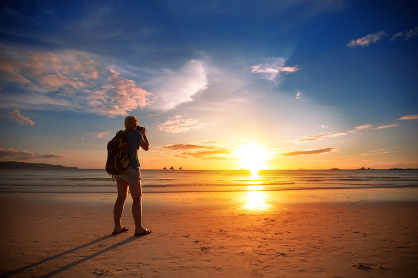 一个男人摄影师用摄影机拍摄海上唯美夕阳风景