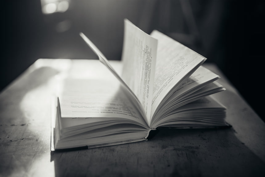 黑白照片显示了一本打开的书放在木质桌子上