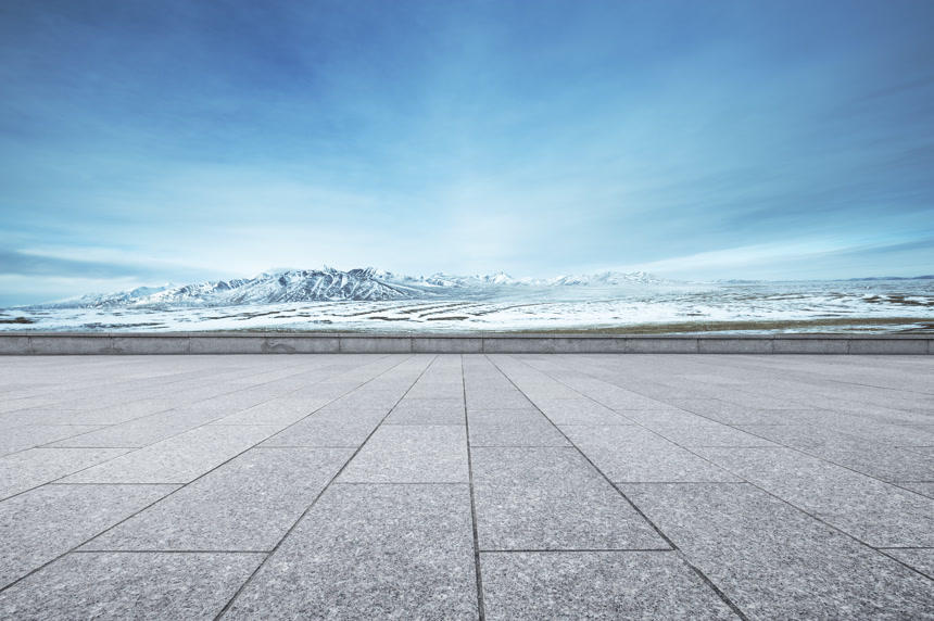 在空旷的地面拍摄远方美丽的雪山风景图片