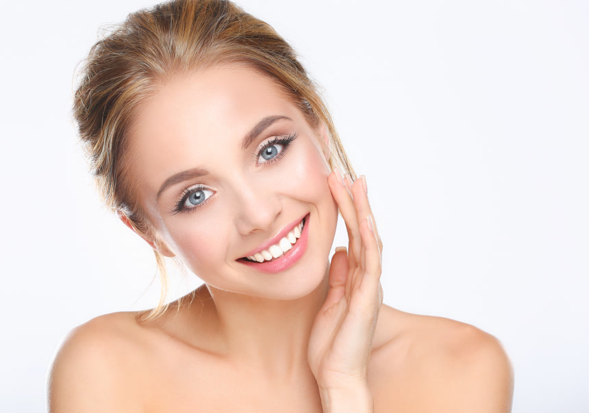 一位年轻女子在白色背景上抚摸着自己的脸美白护肤