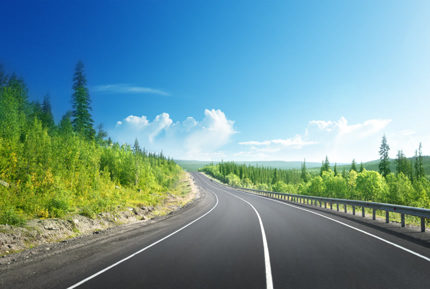 风景照中央有一条笔直的道路两旁是茂密的树木和植被