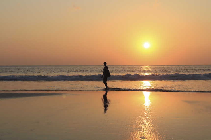 女人日落时分在海滩上玩耍的剪影海边日落