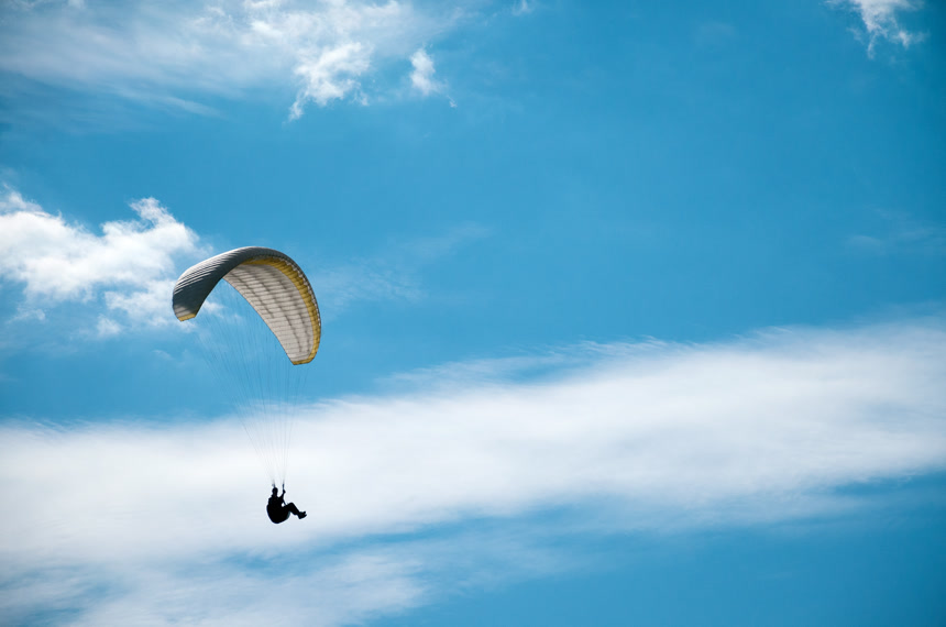 在蔚蓝的天空中正在有人玩滑翔伞休闲娱乐