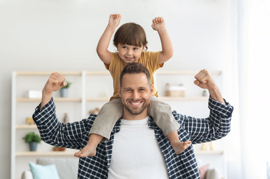 强壮的年轻人背着他的儿子对着镜头微笑生活方式