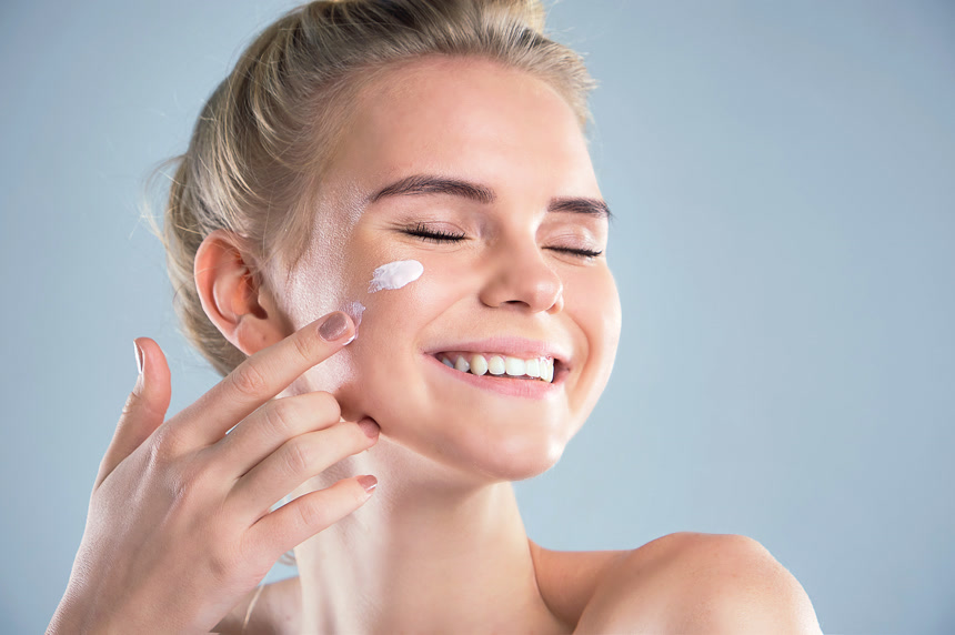 夏天保湿护肤防晒霜在她脸上涂化妆品膏的漂亮模型年轻女人的笑脸美容护肤