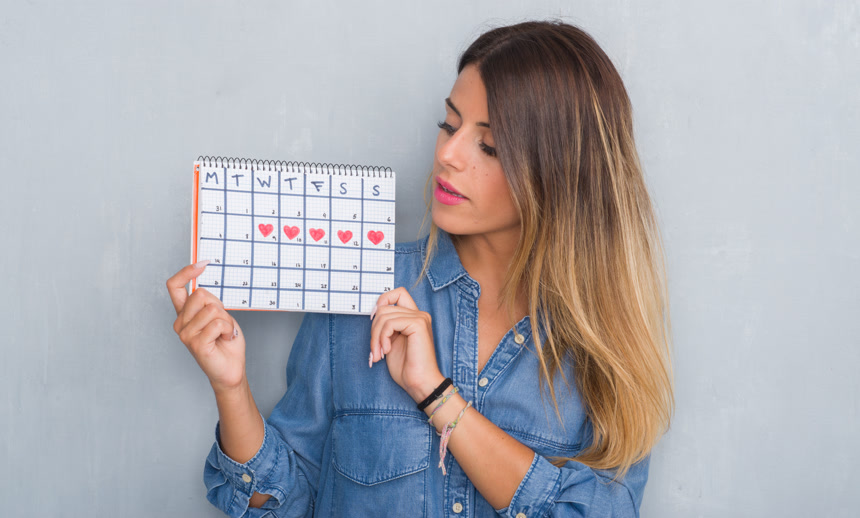 灰色背景墙前一位身穿牛仔衣的外国女性双手拿着日历的特写  人像摄影