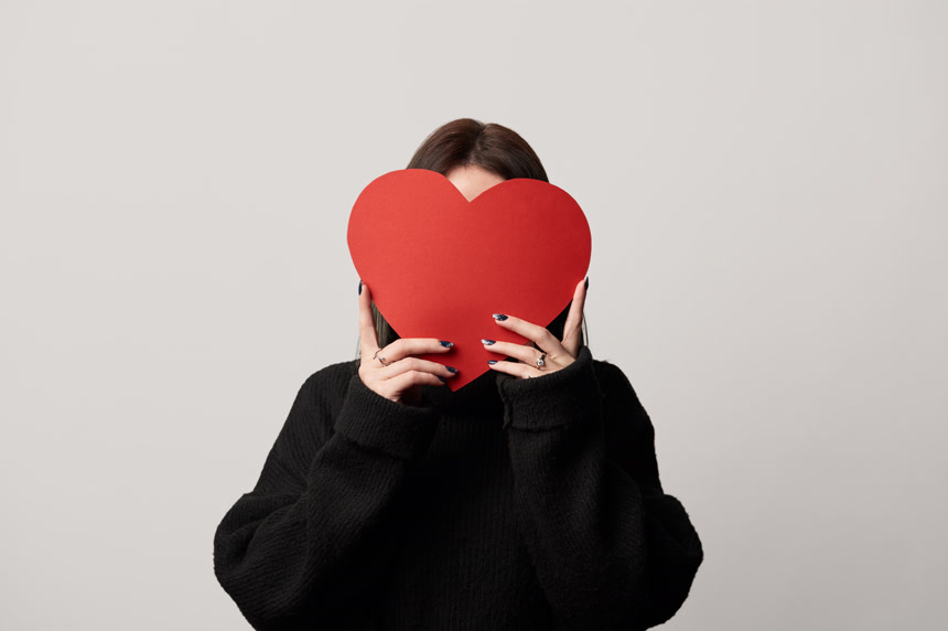 女孩在黑色与模糊的脸和剪纸心脏卡孤立在灰色