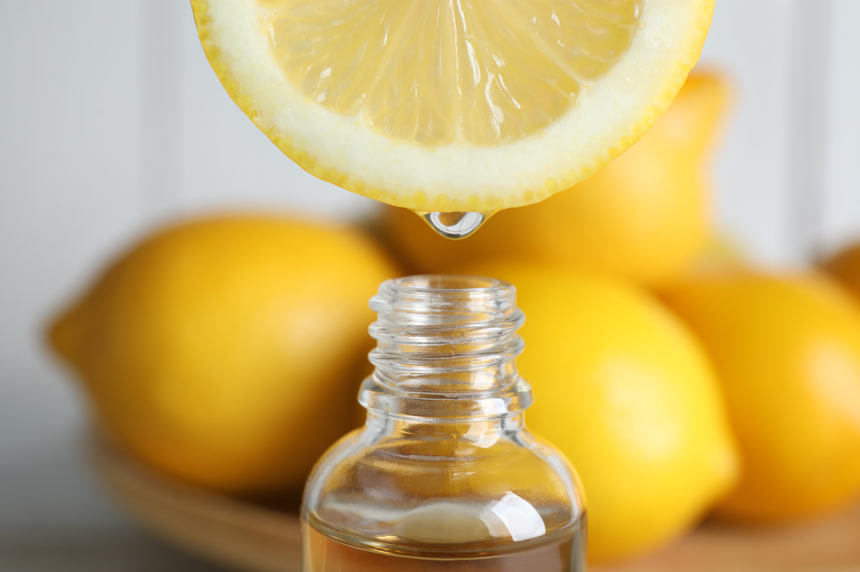 Citrus essential oil dripping from lemon slice into bottle, closeup维生素柠檬汁