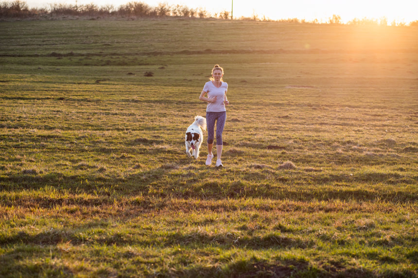 夕阳下在草地奔跑的女人和狗生活方式