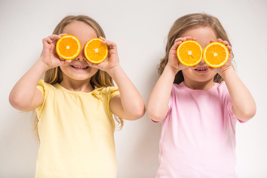 拿着两块切开的橙子举到眼睛上的小女孩六一儿童节人像
