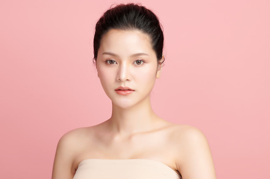 粉红色背景上拥有干净清新的皮肤的年轻女性美业美容