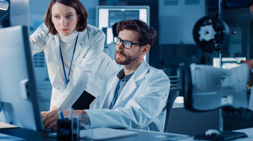 机械发动机开发工程师在办公桌前使用计算机，与项目经理交谈，展示原型组件。专业团队在现代工业设计实验室工作