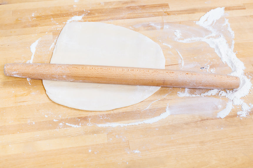 桌子上擀好的面皮和棍子摄影素材