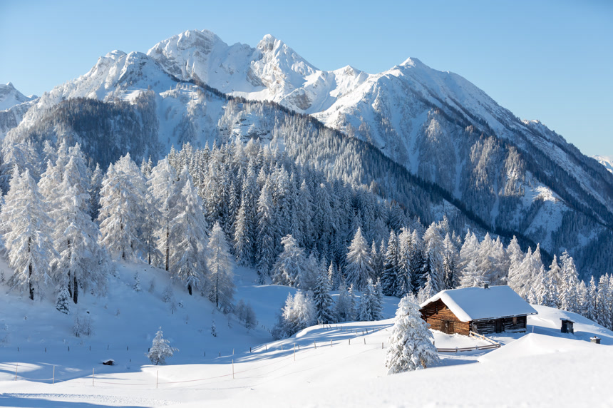 冬季自然背景以传统木制小屋和高山为背景的雪景自然景观