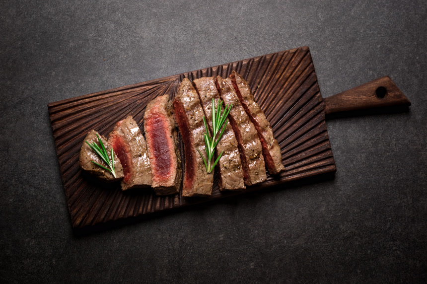 有迷迭香和香料的砧板上的牛排