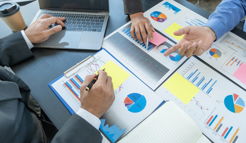 摄影风格手握钢笔女商人和女商人小组开会，规划增加商业收入的战略。对新目标的成功进行头脑风暴式的财务图解分析和讨论.