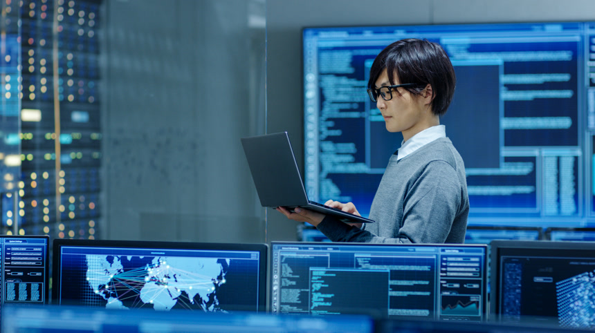 IT技术员在笔记本电脑上工作后台显示器监测数据