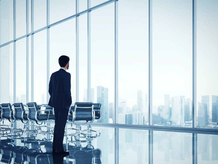 写字楼落地窗前俯瞰城市的成功商人商业素材