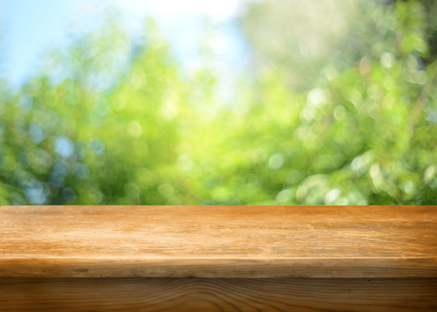 户外绿色模糊背景前的木质桌面 背景素材