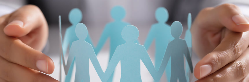  商人用手保护桌子上的剪纸小人商务经济