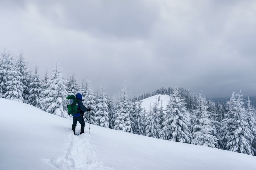 雪山上背着背包的徒步旅行者  冬季旅游主题宣传