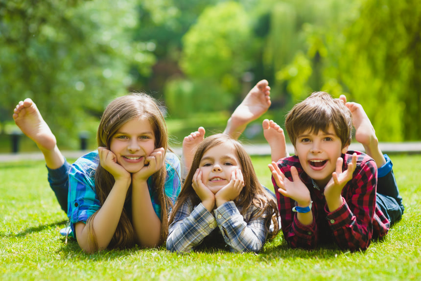 在草丛上趴着双手捧着脸抬着脚的小孩儿童人像