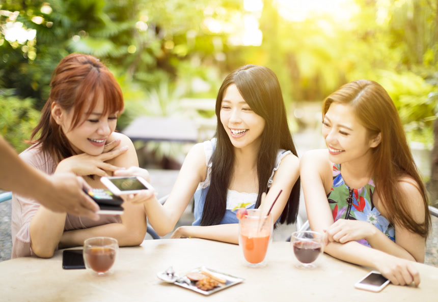 三位年轻中国女性在咖啡厅用智能手机付帐的场景特写科技智能支付