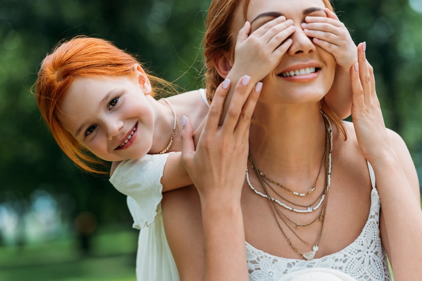 在公园里和母亲玩捉迷藏的女孩休闲娱乐