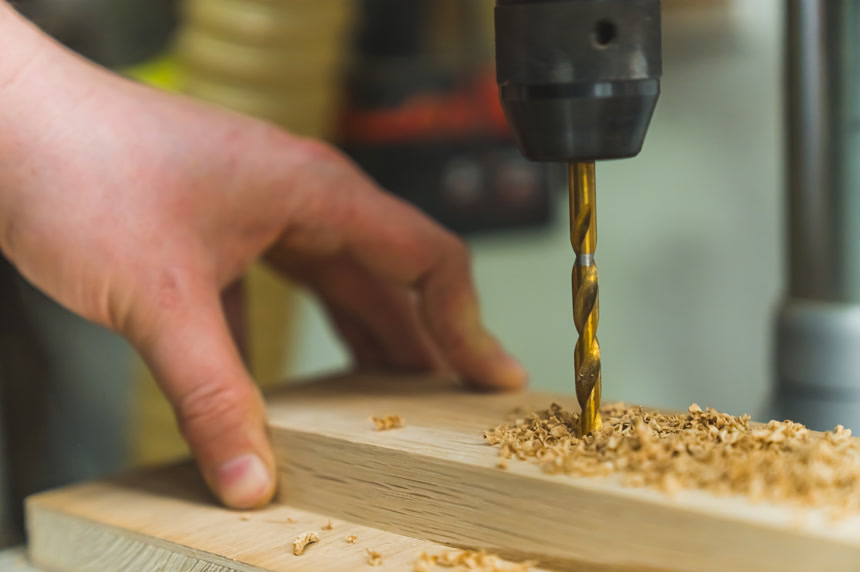 电动螺丝刀金属钻头旋转在木板上打孔的高质量的照片工作场景