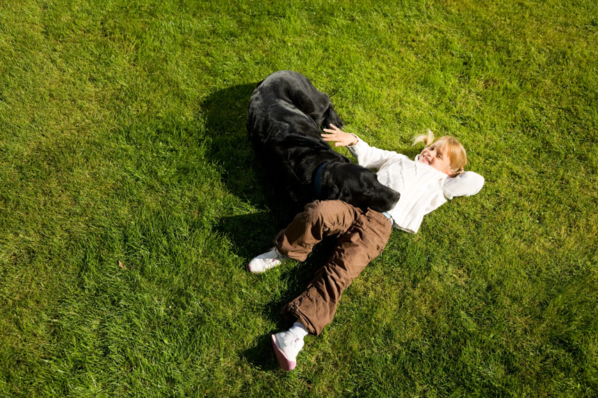 一个小女孩与她的狗躺在草地上人与动物生活场景照片