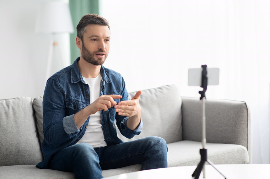 有魅力的中年男人在家里用智能手机直播视频生活方式