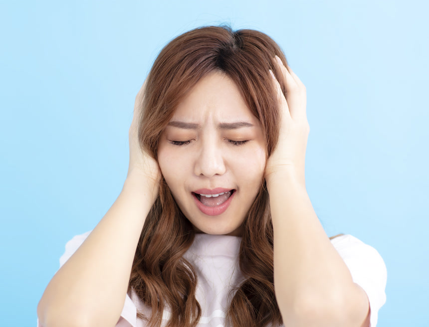 蓝色背景前一名中国女性双手包头露出烦躁的表情      焦虑和紧张情绪释放