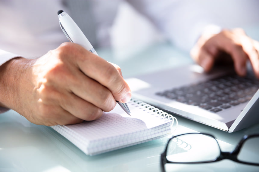 一个商人的手在办公桌上写日记的特写  