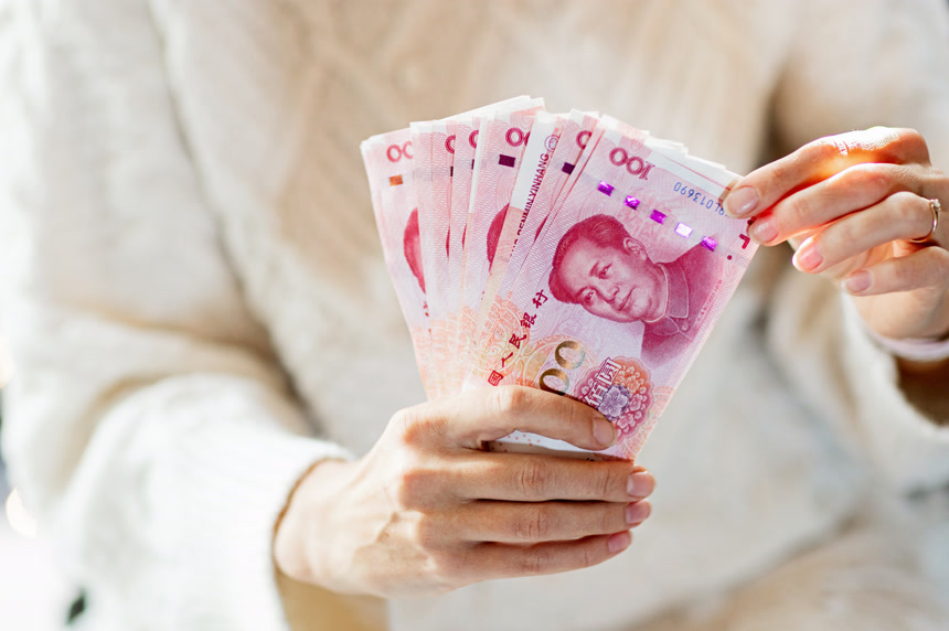 年轻的亚洲女人手握100元人民币现金作为春节的礼物