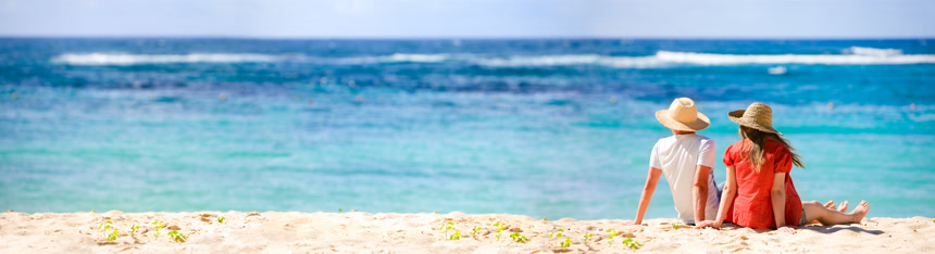 坐在沙滩上的浪漫情侣的全景风景照片