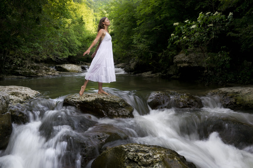 在溪流中穿着白色连衣裙的女孩森林峡谷中