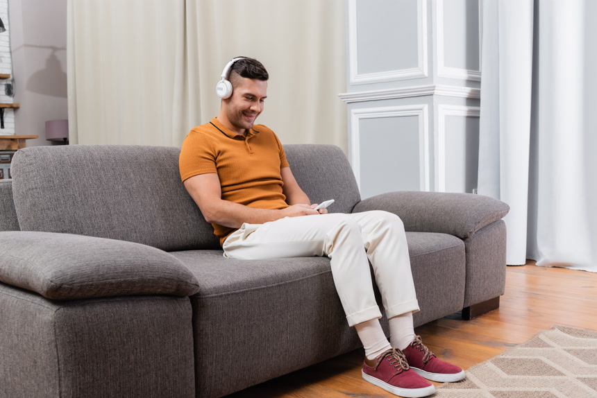 快乐的男人一边用手机聊天一边用耳机听音乐生活方式