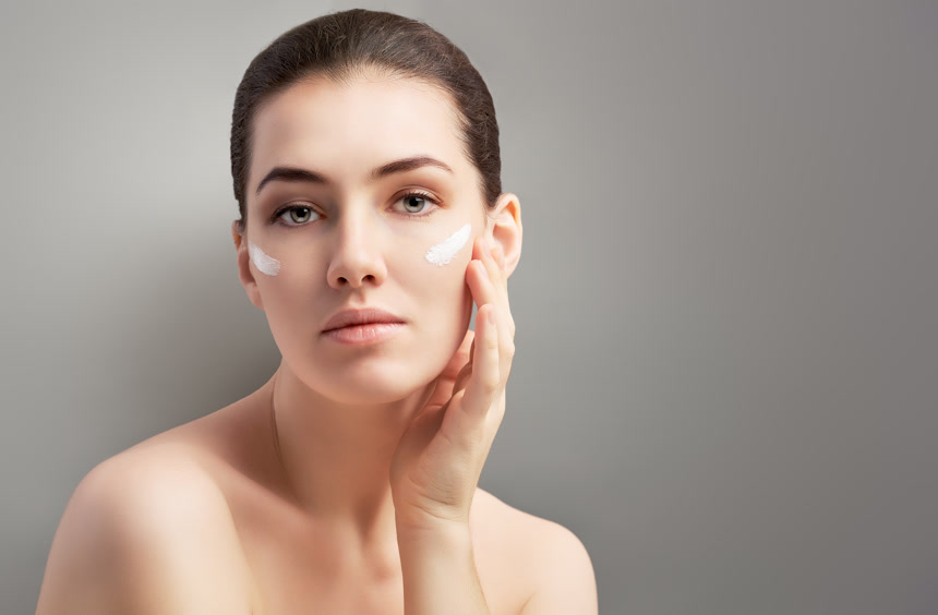 健康的脸女模特脸上摸着护肤品半裸身子手抚摸着脸颊在灰色背景下