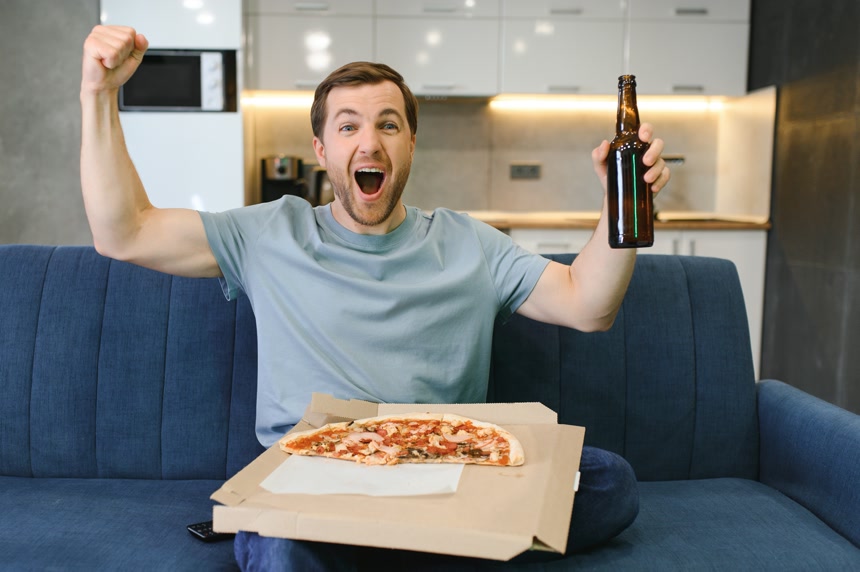 一个很开心地正在喝啤酒吃披萨的外国男人度假休闲娱乐