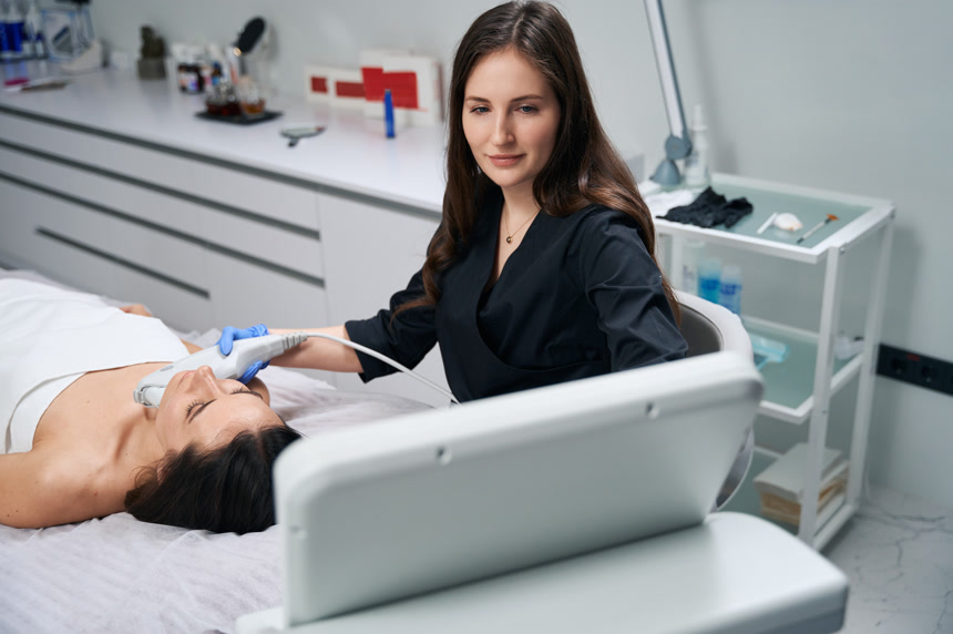 戴防护手套和外套的美容师坐在女性旁边对IPL进行拍照美容护肤