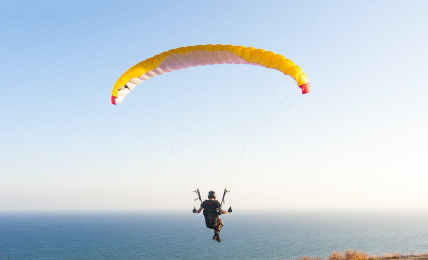 运动员在蓝色大海上用滑翔伞滑行极限运动降落伞