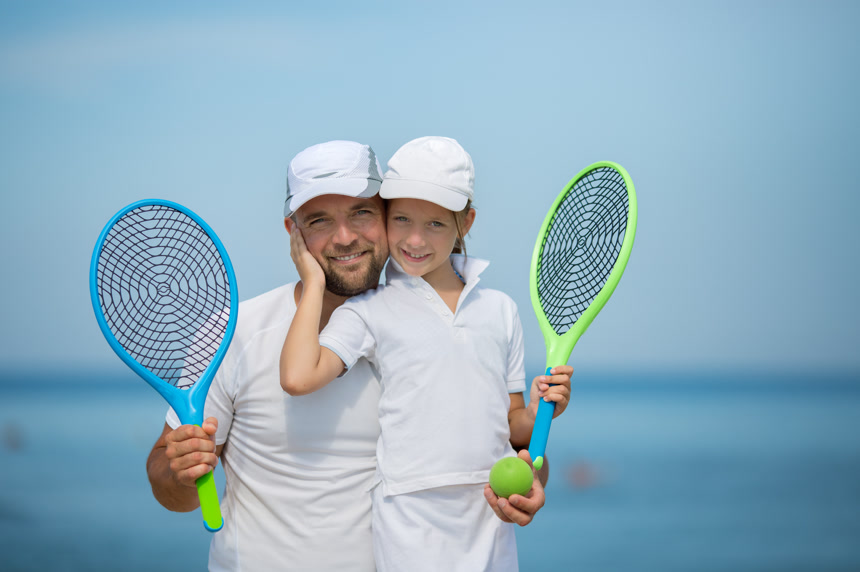 父女俩拿着网球拍在海边拍照体育运动广告素材