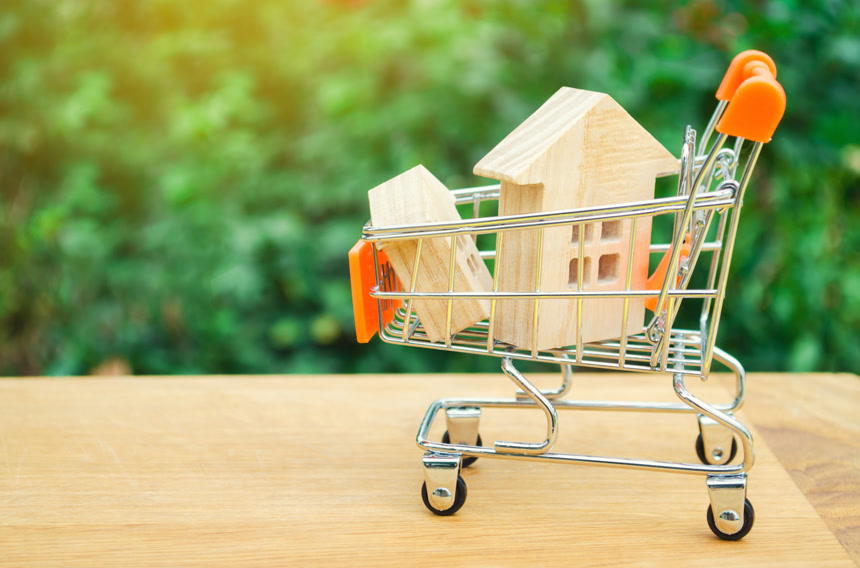 户外绿植模糊背景前小推车里的木房子模型   房地产投资与住房抵押贷款财务概念