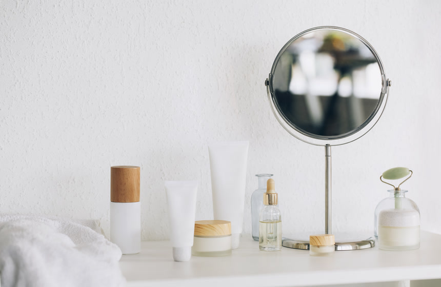 各种化妆品的组成和放在桌上白墙上的圆形镜子美业美容